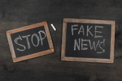 Dwie czarne tabliczki z naniesionymi białą kredą napisami: STOP i FAKE NEWS